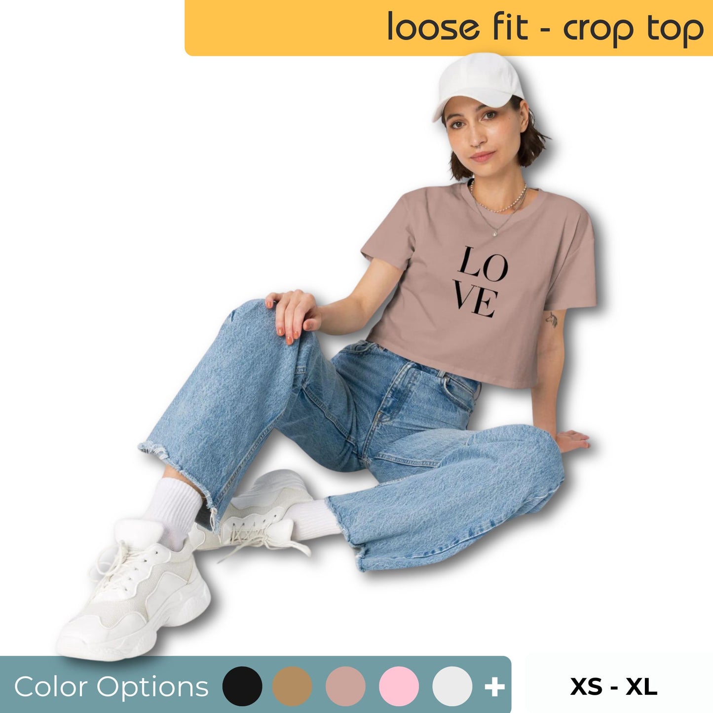 Casual-chic woman in a hazy pink loose-fit crop top with bold 'LOVE' print, paired with baggy denim jeans and white sneakers, featuring color options and sizes XS to XL.