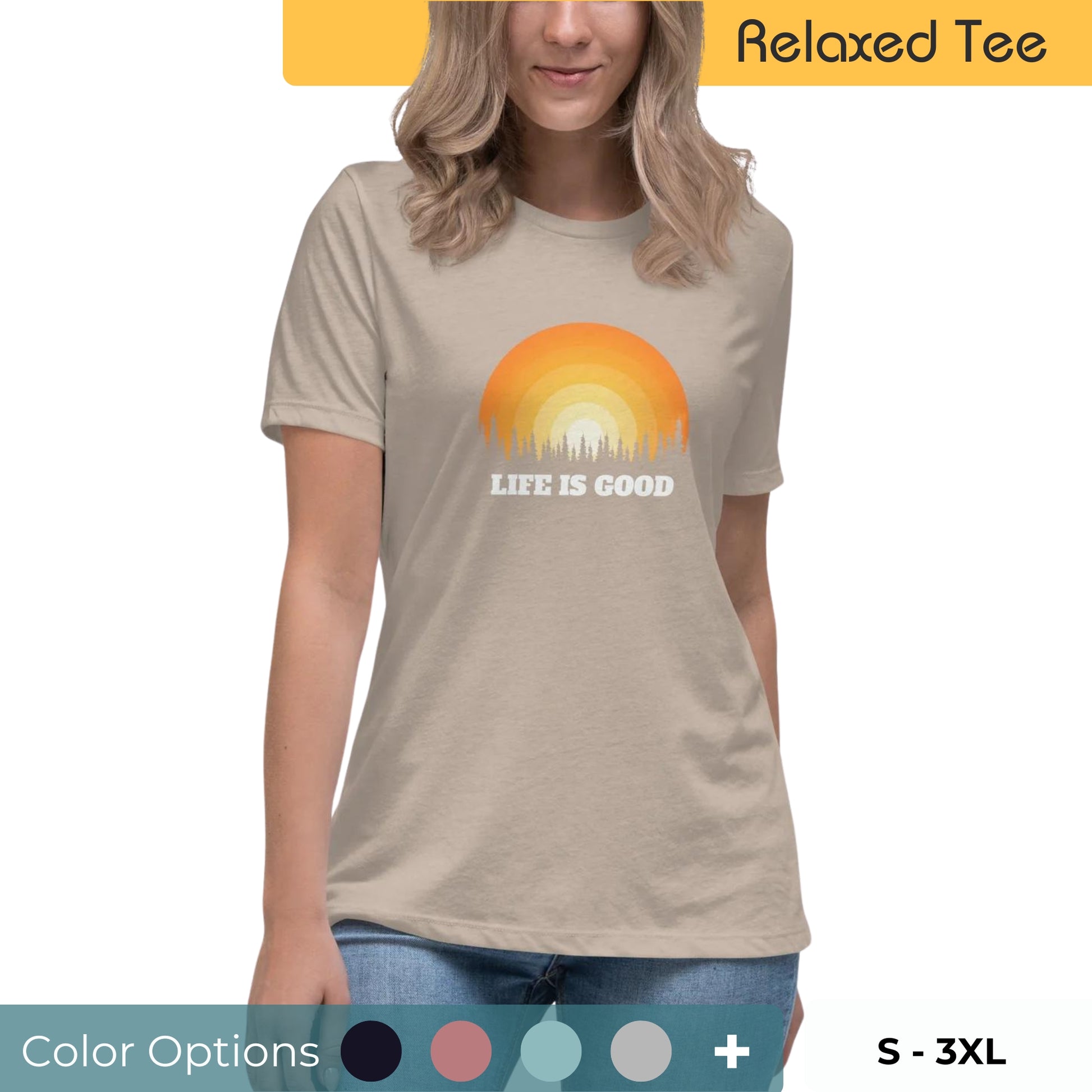 Smiling woman with blonde hair wearing a beige relaxed tee with a vibrant sunset graphic and 'Life is Good' slogan, available in multiple colors, sizes S-3XL