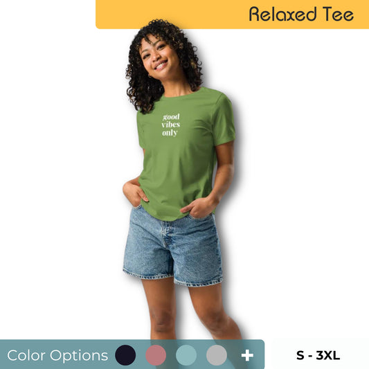 Cheerful woman with curly hair posing in a relaxed fit olive green tee with the text 'good vibes only' in white, paired with denim shorts, available in various colors, sizes S-3XL