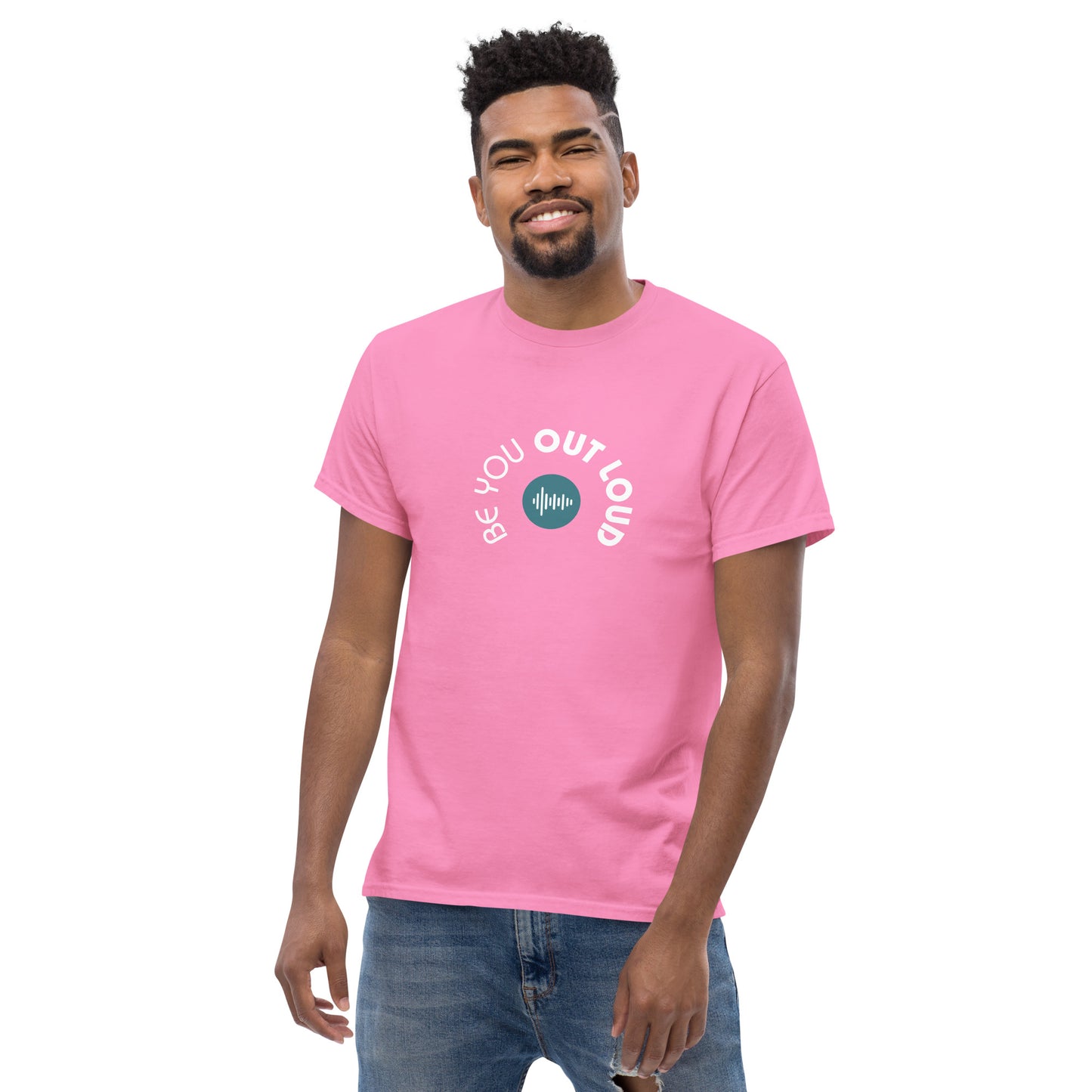 Man smiling in a pink classic tee featuring the 'Be You Out Loud' white and blue logo on the front