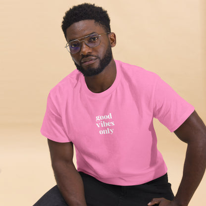 Man wearing a pink classic tee with 'good vibes only' text, a testament to a lifestyle of positivity and authentic personal expression.