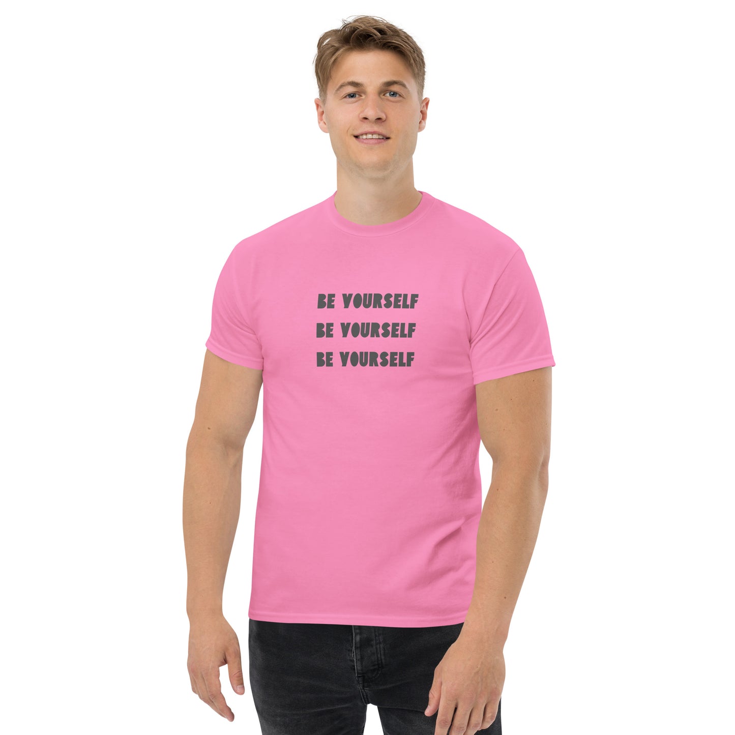 Smiling man in a pink classic tee with 'BE YOURSELF' text fading vertically, echoing authenticity and personal expression.