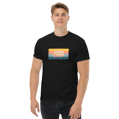 Smiling man wearing a black classic tee with a colorful 'good vibes' retro graphic, symbolizing relaxed and inspirational personal style.