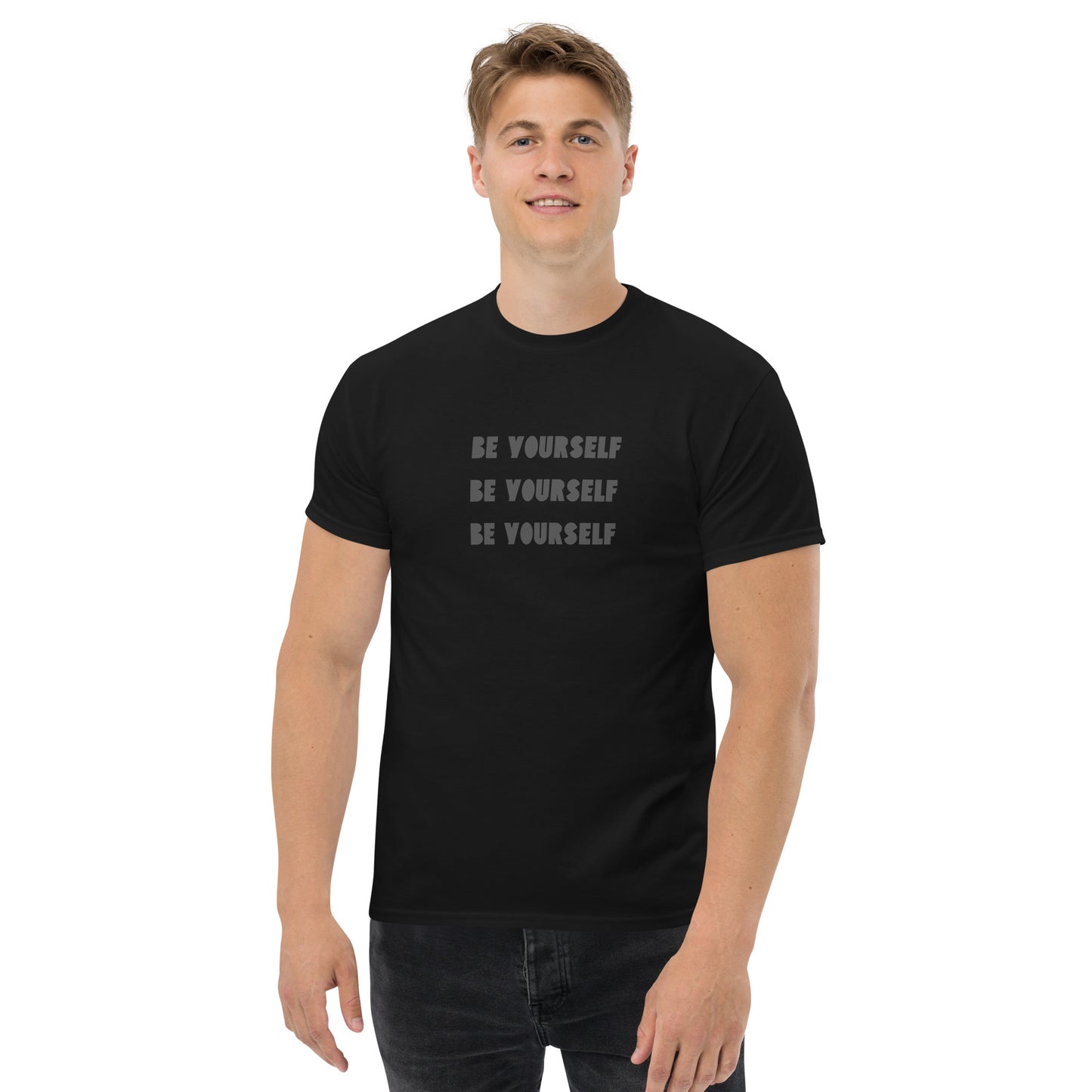 Smiling man in a black classic tee with 'BE YOURSELF' text fading vertically, echoing authenticity and personal expression.