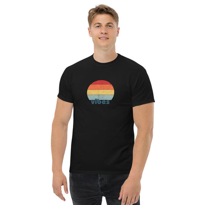 Confident man sporting a black classic tee with a colorful retro sunset design and 'vibes' text, evoking a relaxed and inspiring mood.