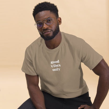 Man wearing a savana sand classic tee with 'good vibes only' text, a testament to a lifestyle of positivity and authentic personal expression.