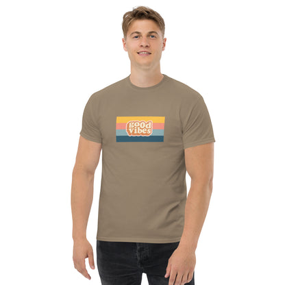 Smiling man wearing a brown savana classic tee with a colorful 'good vibes' retro graphic, symbolizing relaxed and inspirational personal style.