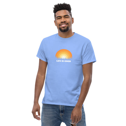 Happy man wearing a carolina blue classic tee with a vibrant sunset graphic and 'Life Is Good' slogan, inspiring positivity and joy.