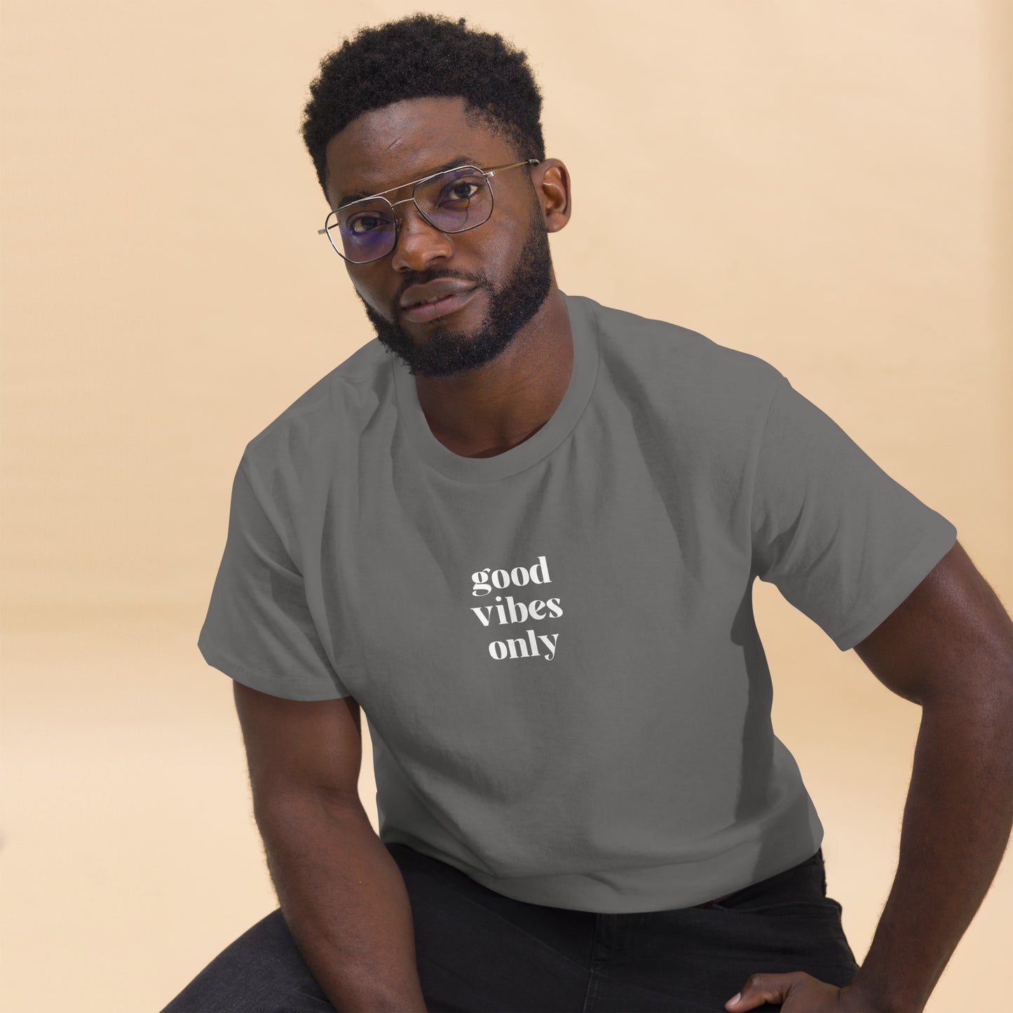 Man wearing a stone classic tee with 'good vibes only' text, a testament to a lifestyle of positivity and authentic personal expression.