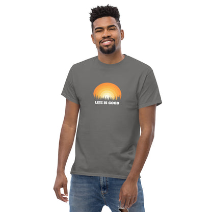 Happy man wearing a stone classic tee with a vibrant sunset graphic and 'Life Is Good' slogan, inspiring positivity and joy.