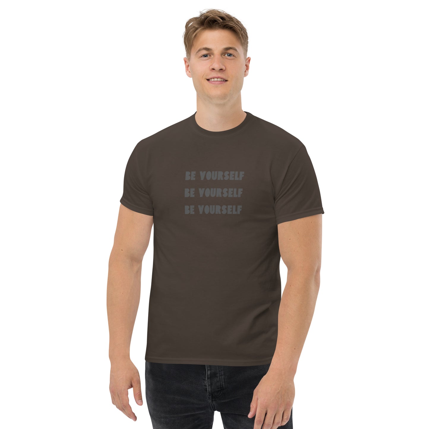 Smiling man in a chocolate brown classic tee with 'BE YOURSELF' text fading vertically, echoing authenticity and personal expression.