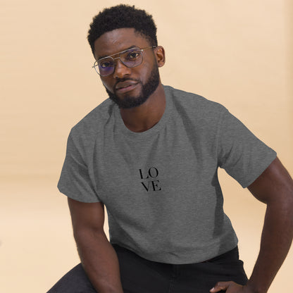 Man in heather grey t-shirt with "LOVE" print leaning forward against a light background, portraying casual style and positive messaging.