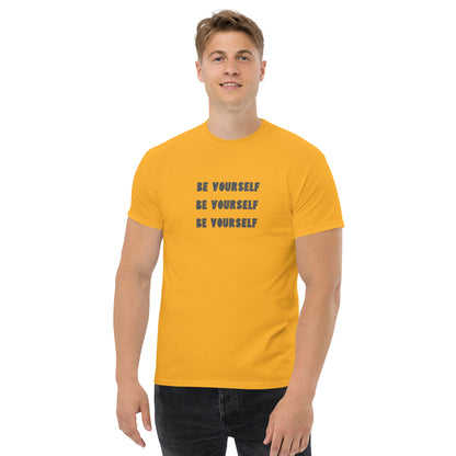 Smiling man in a yellow classic tee with 'BE YOURSELF' text fading vertically, echoing authenticity and personal expression.