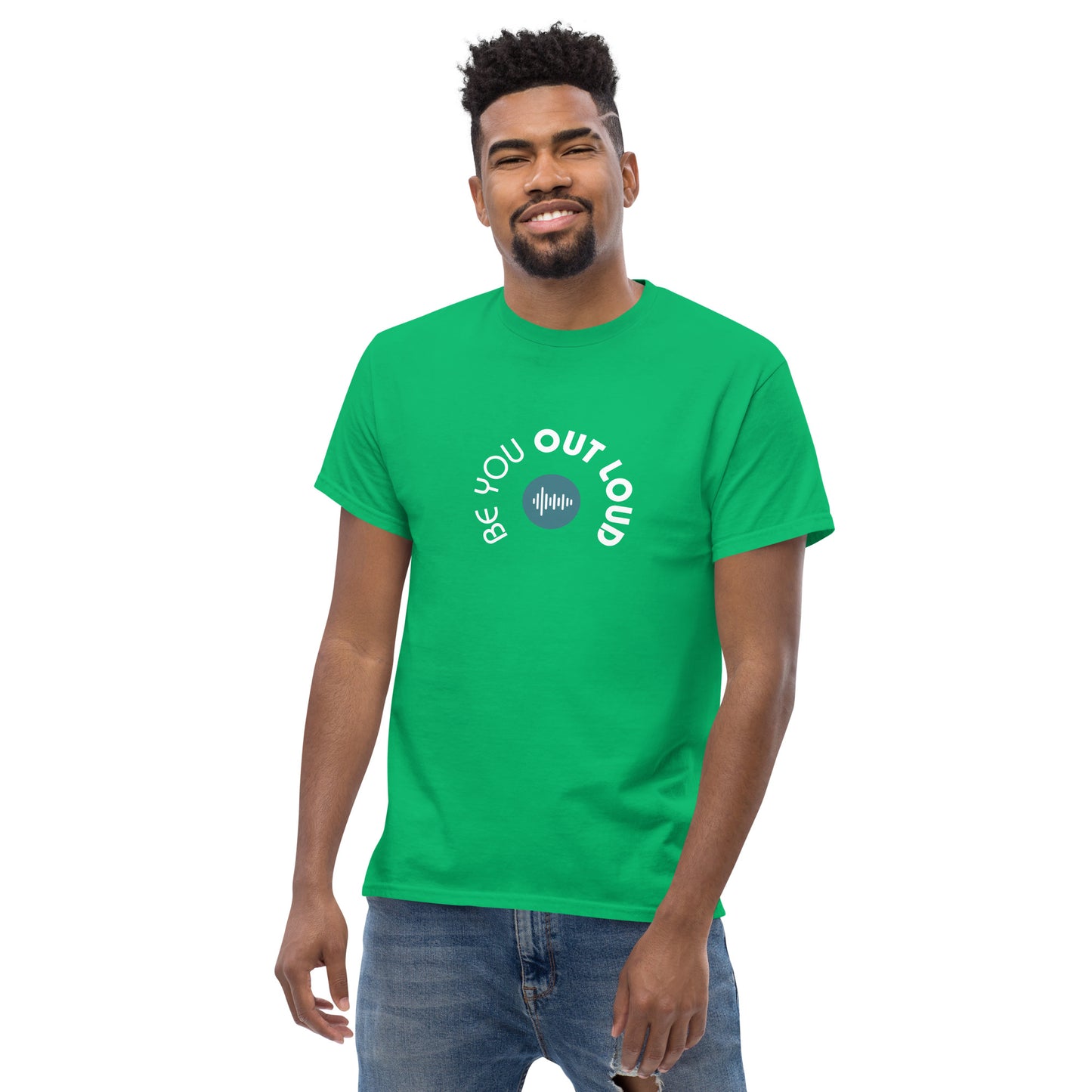 Man smiling in a green classic tee featuring the 'Be You Out Loud' white and blue logo on the front