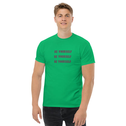 Smiling man in a irish green classic tee with 'BE YOURSELF' text fading vertically, echoing authenticity and personal expression.