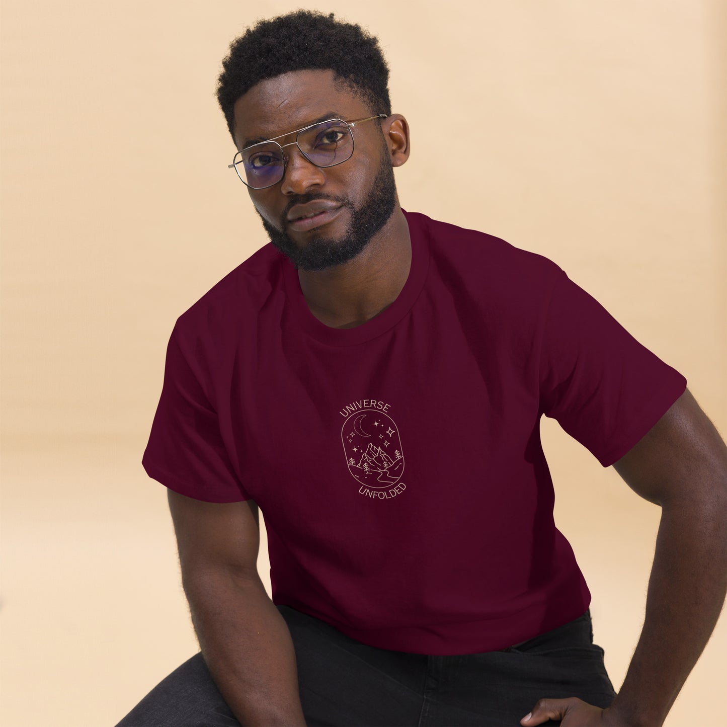 Man in a maroon tee with a cosmic design saying 'Universe Unfolded', epitomizing bold self-expression.