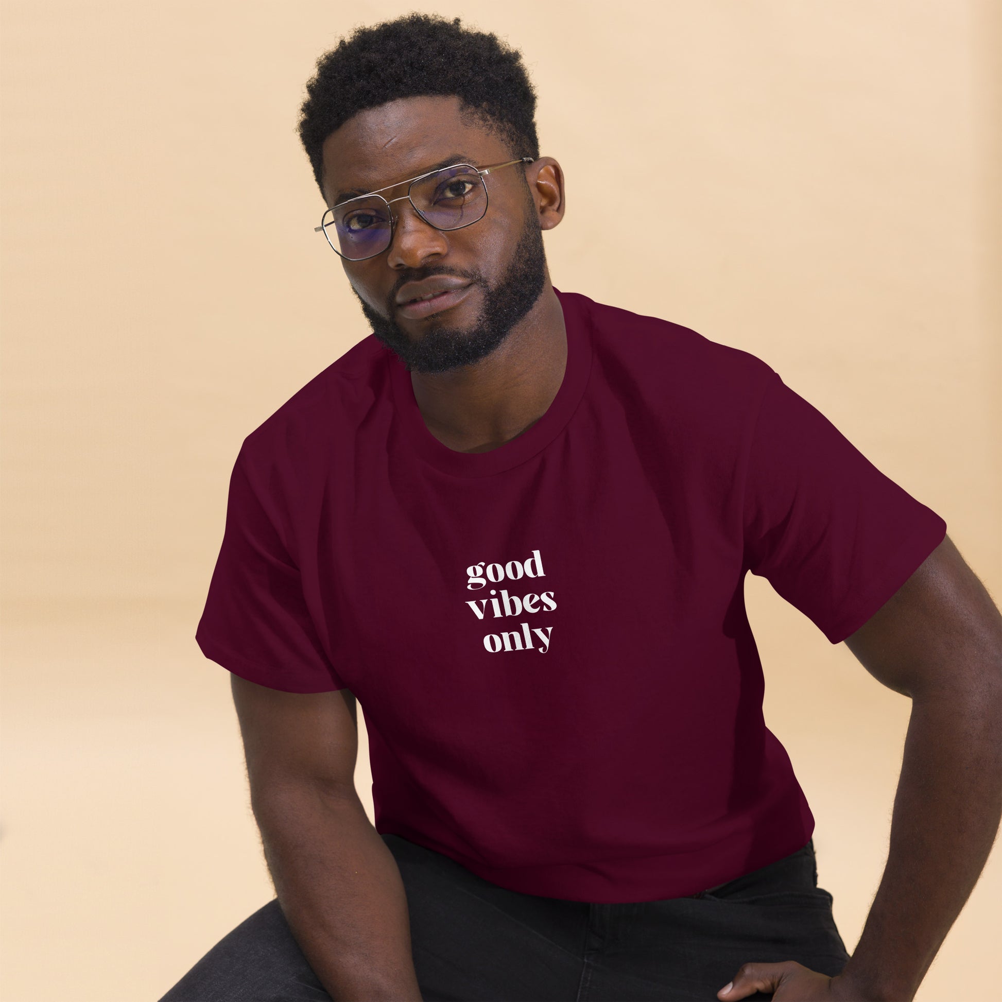 Man wearing a maroon classic tee with 'good vibes only' text, a testament to a lifestyle of positivity and authentic personal expression.