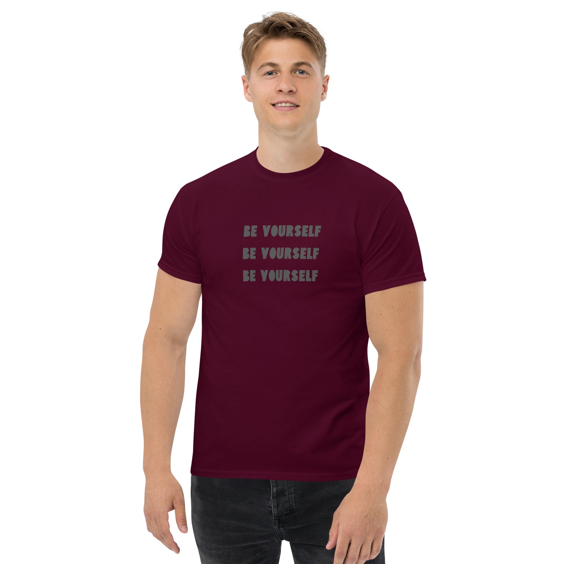 Smiling man in a maroon classic tee with 'BE YOURSELF' text fading vertically, echoing authenticity and personal expression.