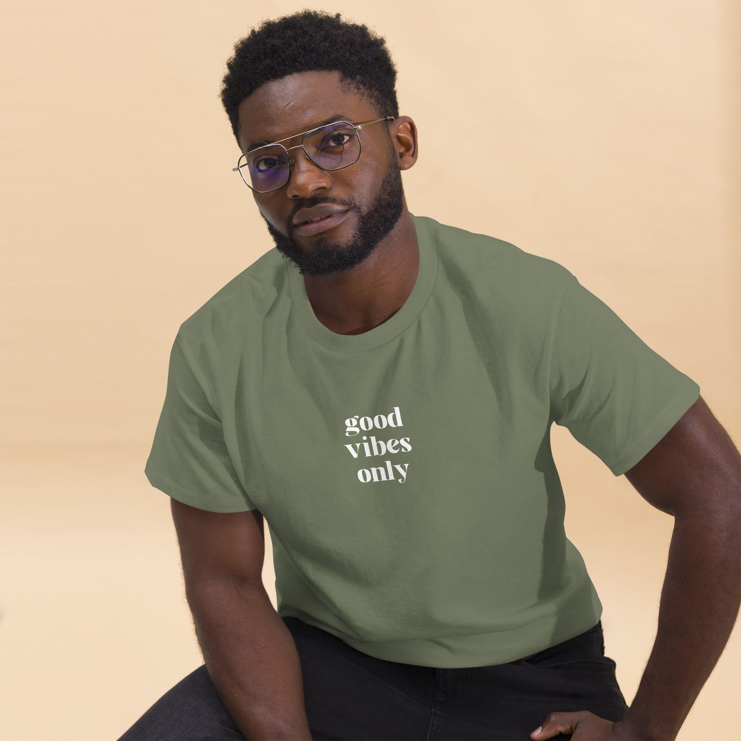 Man wearing a military green classic tee with 'good vibes only' text, a testament to a lifestyle of positivity and authentic personal expression.