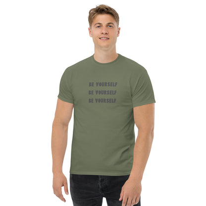 Smiling man in a military green classic tee with 'BE YOURSELF' text fading vertically, echoing authenticity and personal expression.