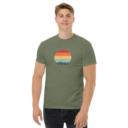 Confident man sporting a military green classic tee with a colorful retro sunset design and 'vibes' text, evoking a relaxed and inspiring mood.