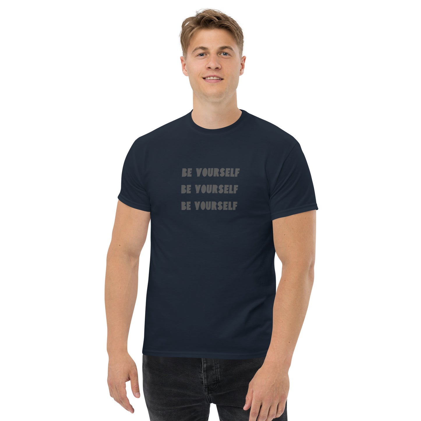 Smiling man in a navy blue classic tee with 'BE YOURSELF' text fading vertically, echoing authenticity and personal expression.