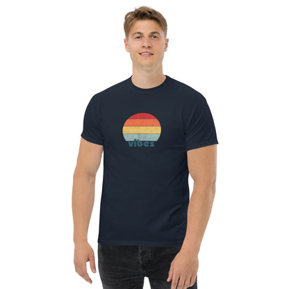 Confident man sporting a navy blue classic tee with a colorful retro sunset design and 'vibes' text, evoking a relaxed and inspiring mood.