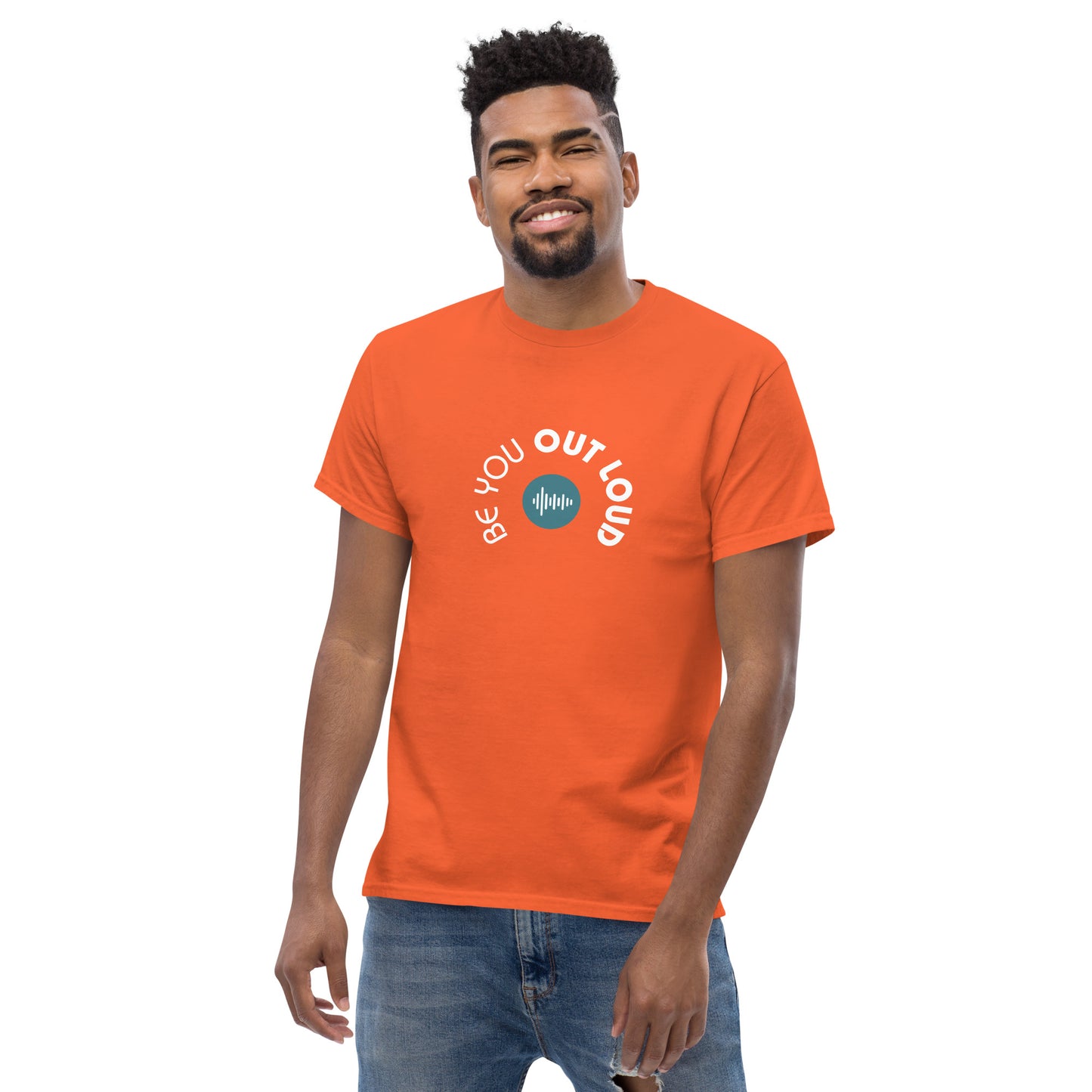 Man smiling in a orange classic tee featuring the 'Be You Out Loud' white and blue logo on the front