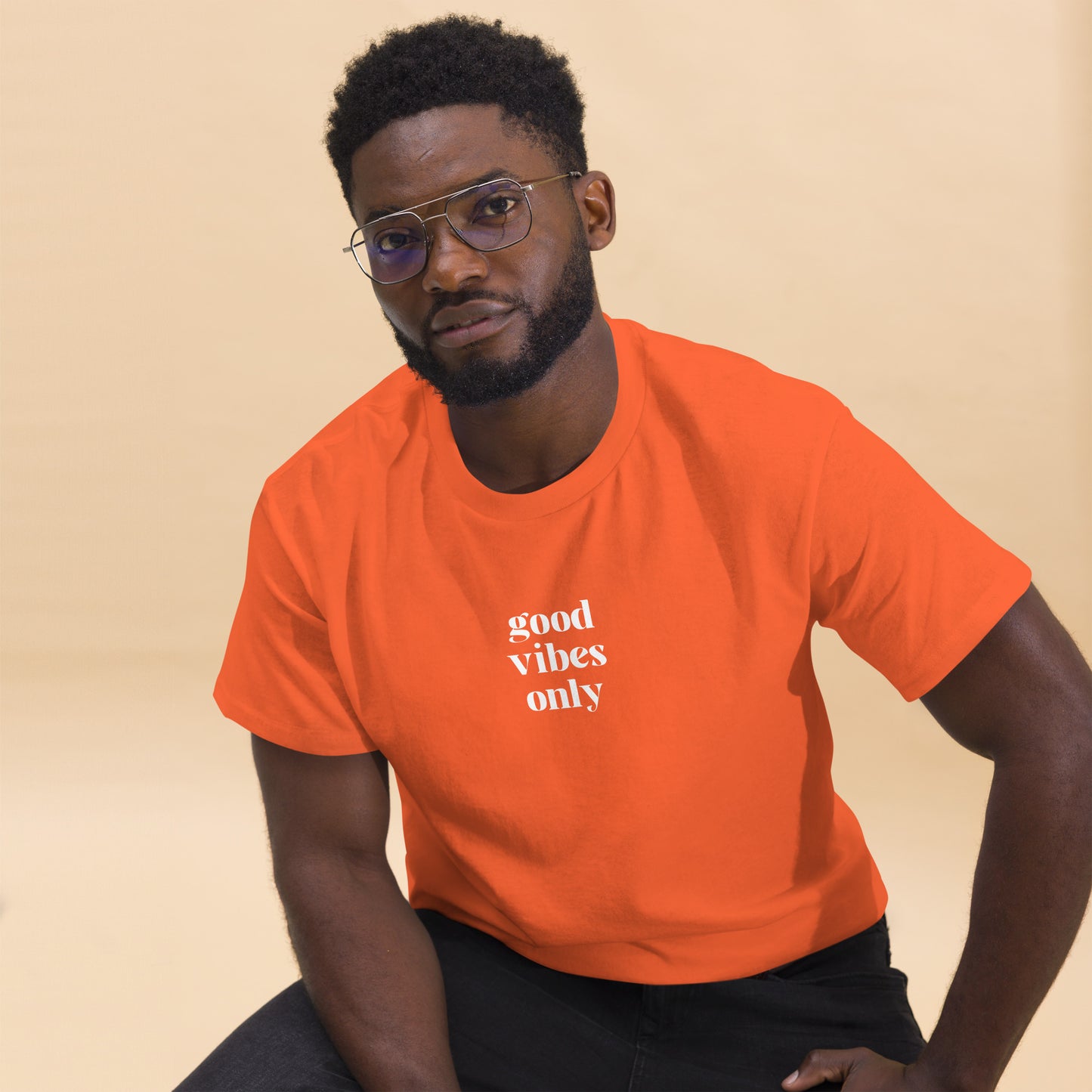 Man wearing a orange classic tee with 'good vibes only' text, a testament to a lifestyle of positivity and authentic personal expression.