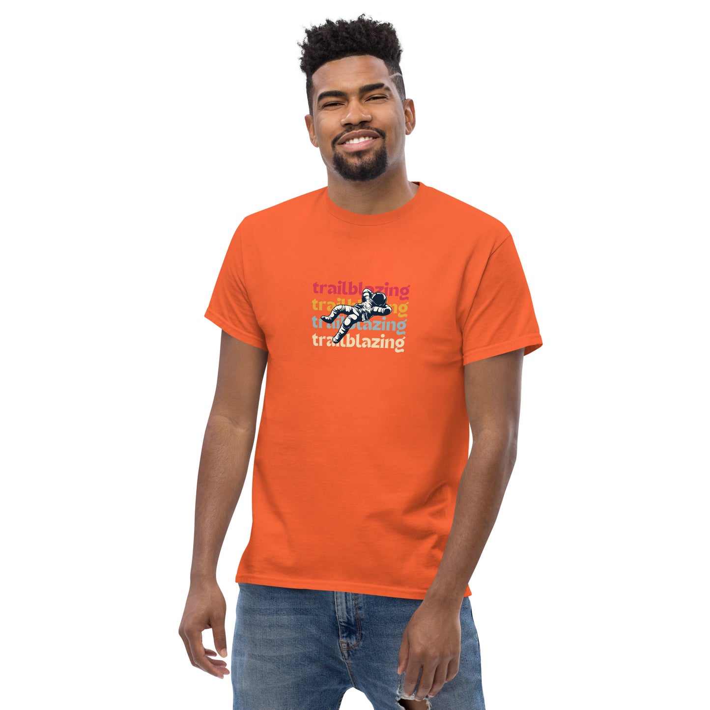 Smiling man in a orange classic tee with vibrant 'trailblazing' text, embodying the spirit of boldness and individual trailblazing attitude.