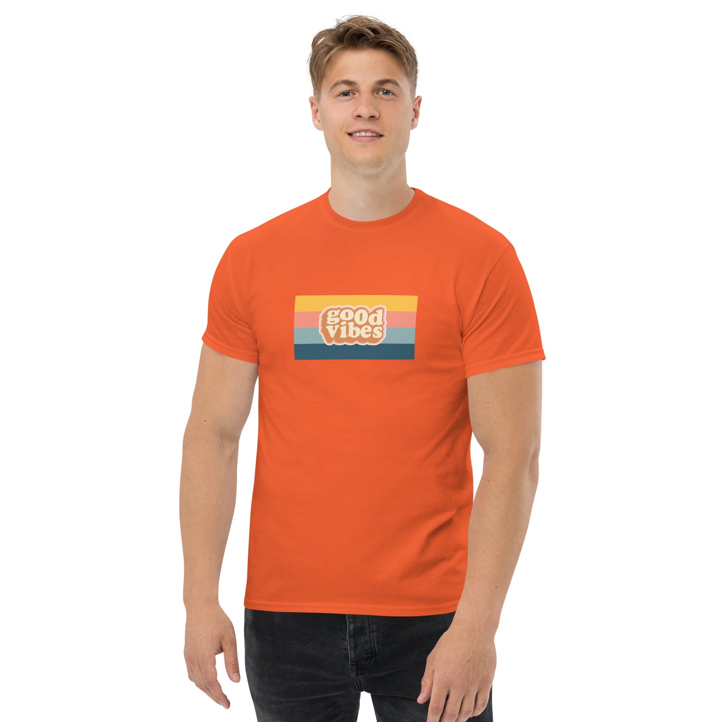 Smiling man wearing a orange classic tee with a colorful 'good vibes' retro graphic, symbolizing relaxed and inspirational personal style.