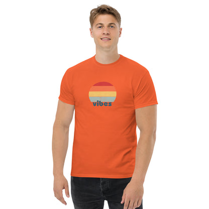 Confident man sporting a orange classic tee with a colorful retro sunset design and 'vibes' text, evoking a relaxed and inspiring mood.