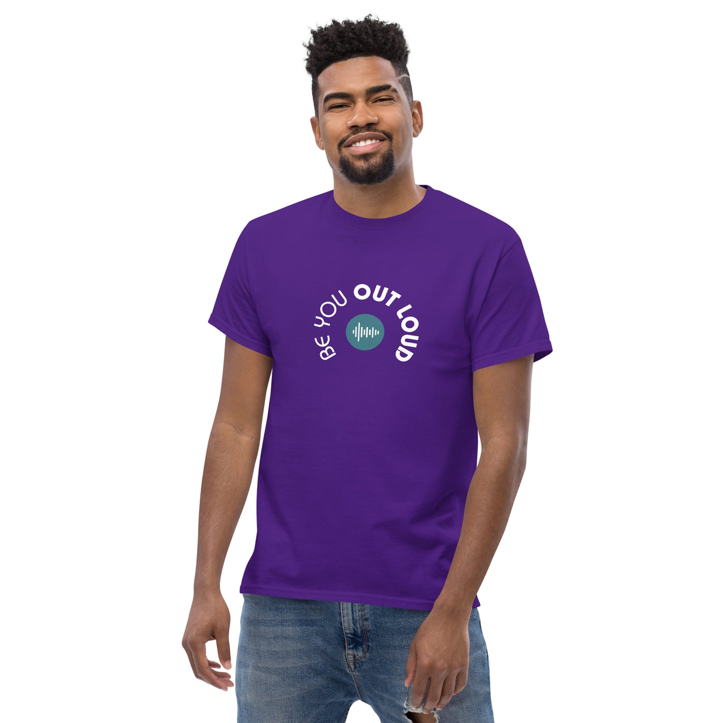 Man smiling in a purple classic tee featuring the 'Be You Out Loud' white and blue logo on the front