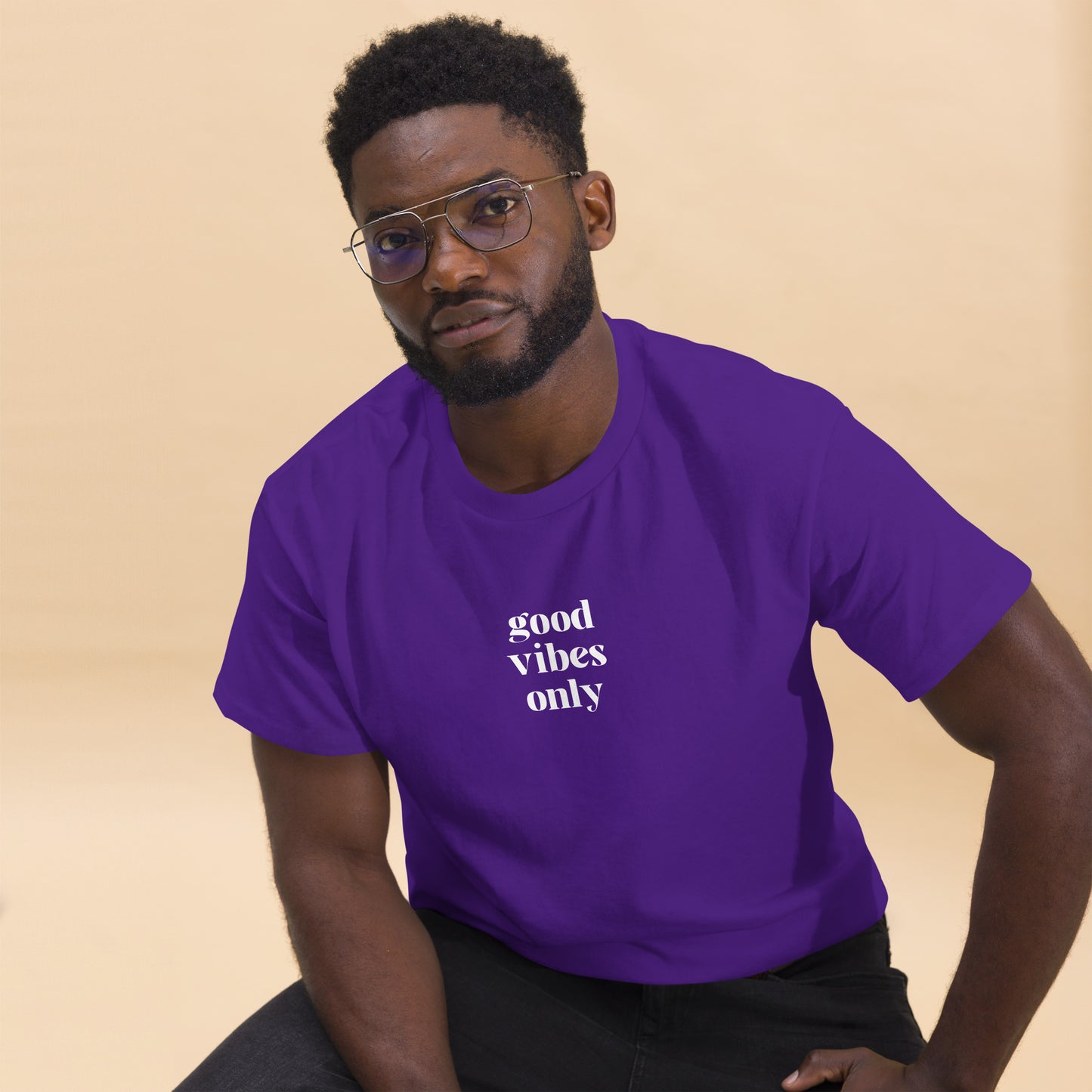 Man wearing a purple classic tee with 'good vibes only' text, a testament to a lifestyle of positivity and authentic personal expression.