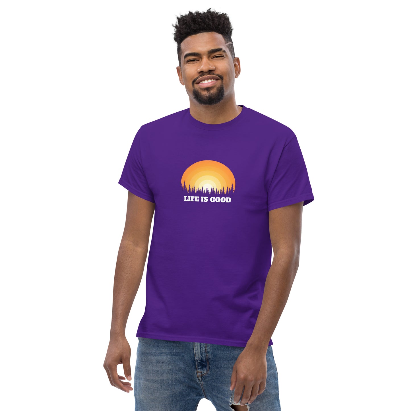 Happy man wearing a purple classic tee with a vibrant sunset graphic and 'Life Is Good' slogan, inspiring positivity and joy.