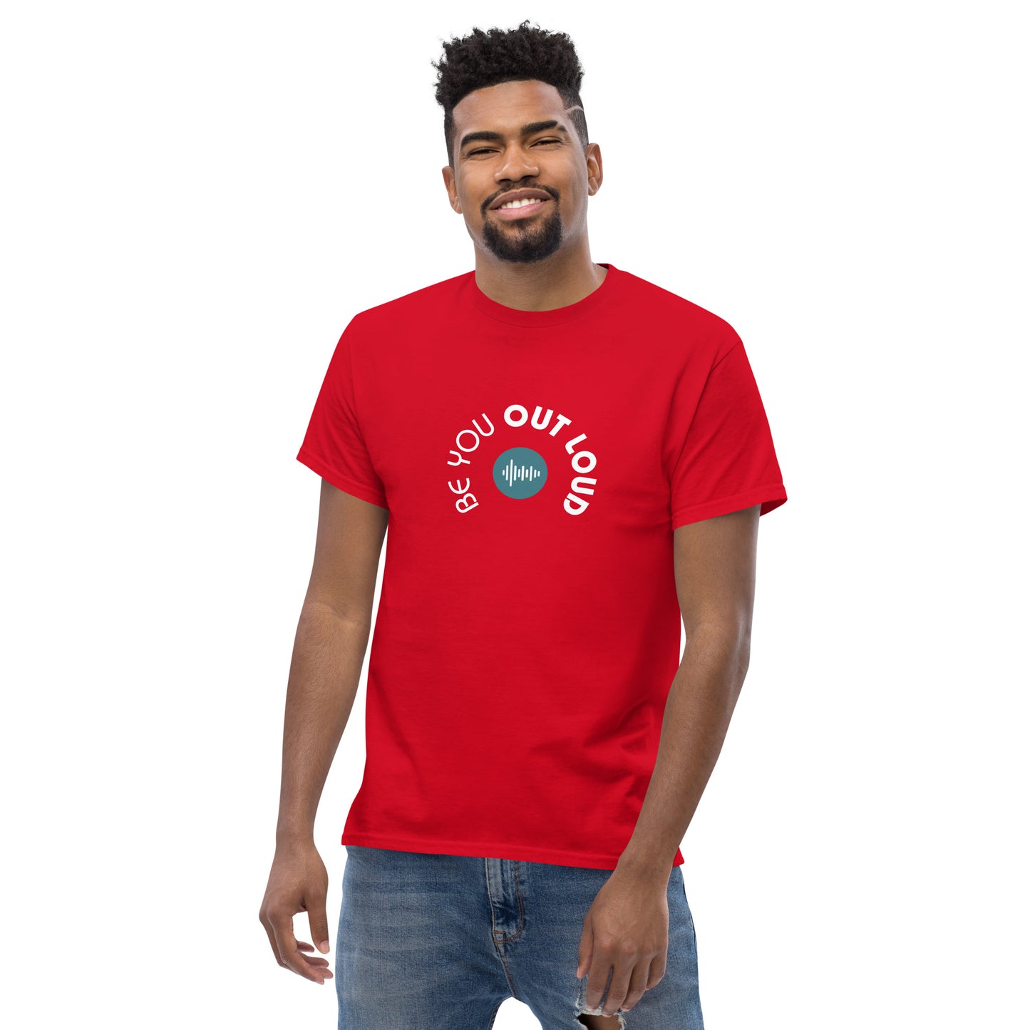 Man smiling in a red classic tee featuring the 'Be You Out Loud' white and blue logo on the front