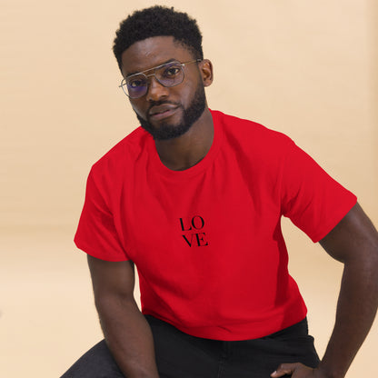 Man in red t-shirt with "LOVE" print leaning forward against a light background, portraying casual style and positive messaging.