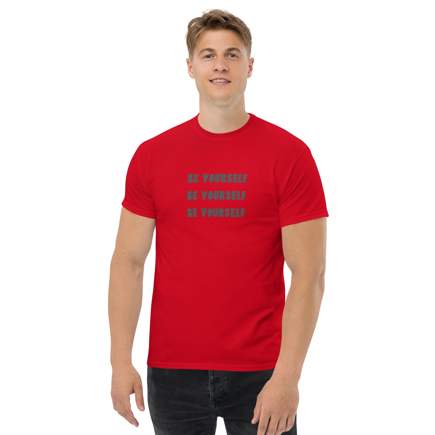 Smiling man in a red classic tee with 'BE YOURSELF' text fading vertically, echoing authenticity and personal expression.