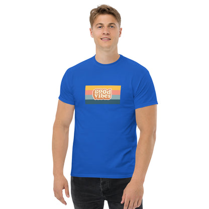 Smiling man wearing a royal blue classic tee with a colorful 'good vibes' retro graphic, symbolizing relaxed and inspirational personal style.