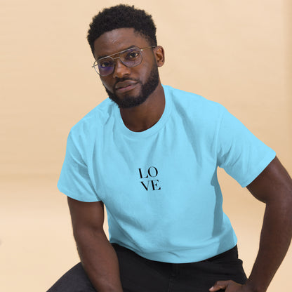 Man in carolina blue t-shirt with "LOVE" print leaning forward against a light background, portraying casual style and positive messaging.