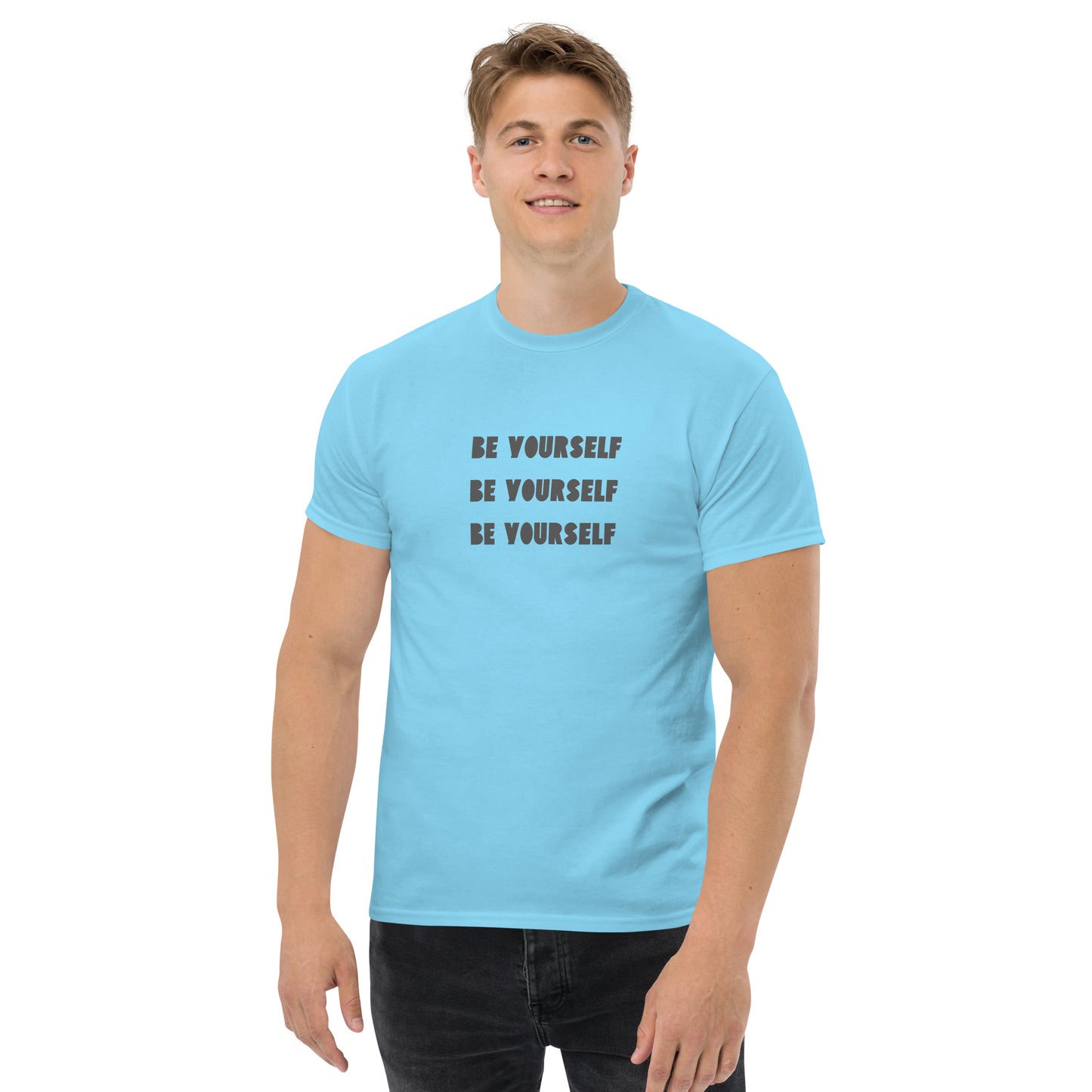 Smiling man in a carolina blue classic tee with 'BE YOURSELF' text fading vertically, echoing authenticity and personal expression.