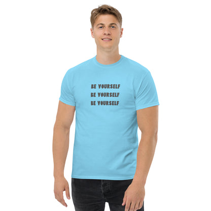 Smiling man in a carolina blue classic tee with 'BE YOURSELF' text fading vertically, echoing authenticity and personal expression.