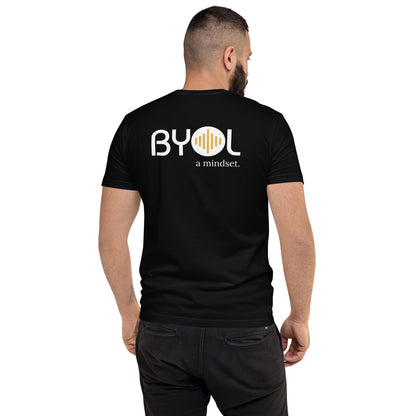 A young man with short dark hair and a beard wearing a black "BYOL: a mindset" T-shirt, viewed from the back. The T-shirt features the "BYOL" logo in white and yellow on the back and is available in multiple colors (red, blue, gray, white, plus more) and sizes (S-3XL). The "be you out loud" logo is displayed at the top.