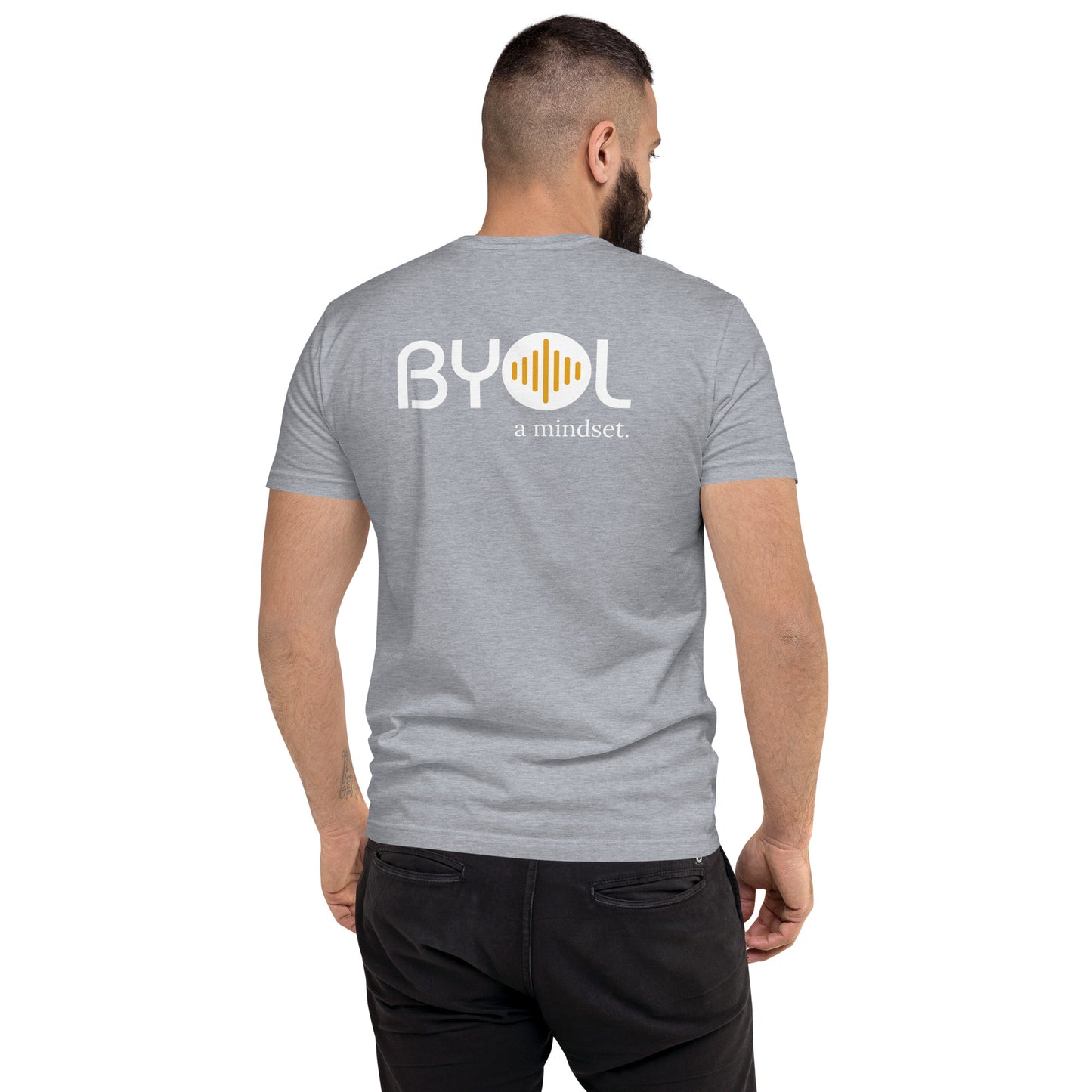 A young man with short dark hair and a beard wearing a grey "BYOL: a mindset" T-shirt, viewed from the back. The T-shirt features the "BYOL" logo in white and yellow on the back and is available in multiple colors (red, blue, gray, white, plus more) and sizes (S-3XL). The "be you out loud" logo is displayed at the top.