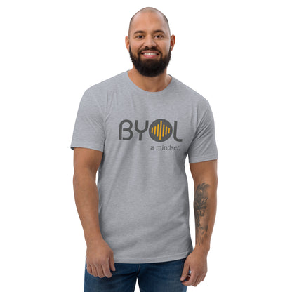 A bearded man with a shaved head wearing heather grey "BYOL: a mindset" T-shirt, smiling and standing with his arms at his sides. The T-shirt features the "BYOL" logo in gray and yellow on the front and is available in multiple colors (red, blue, gray, white, plus more) and sizes (S-3XL). The "be you out loud" logo is displayed at the top.