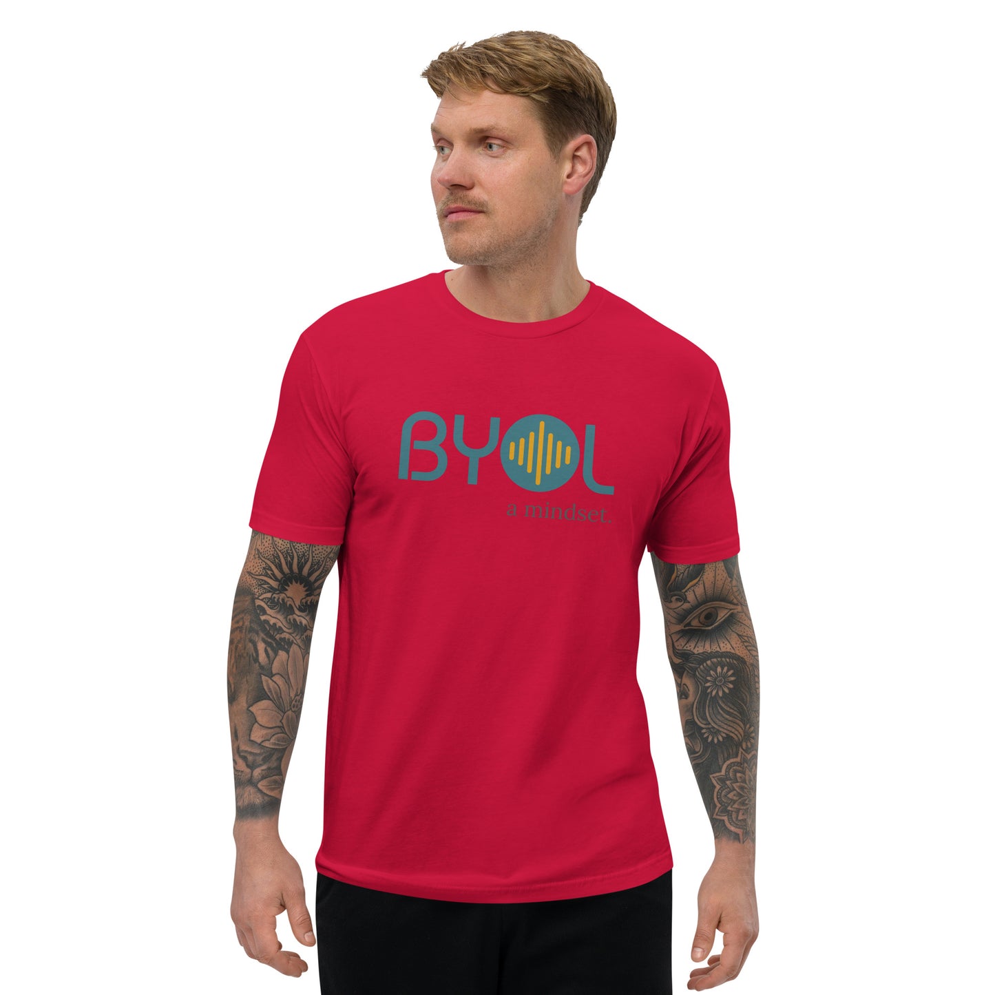 A young man with short blonde hair and arm tattoos wearing a red "BYOL: a mindset" T-shirt, standing and looking to the side. The T-shirt features the "BYOL" logo in teal and yellow on the front and is available in multiple colors (red, blue, gray, white, plus more) and sizes (S-3XL). The "be you out loud" logo is displayed at the top.