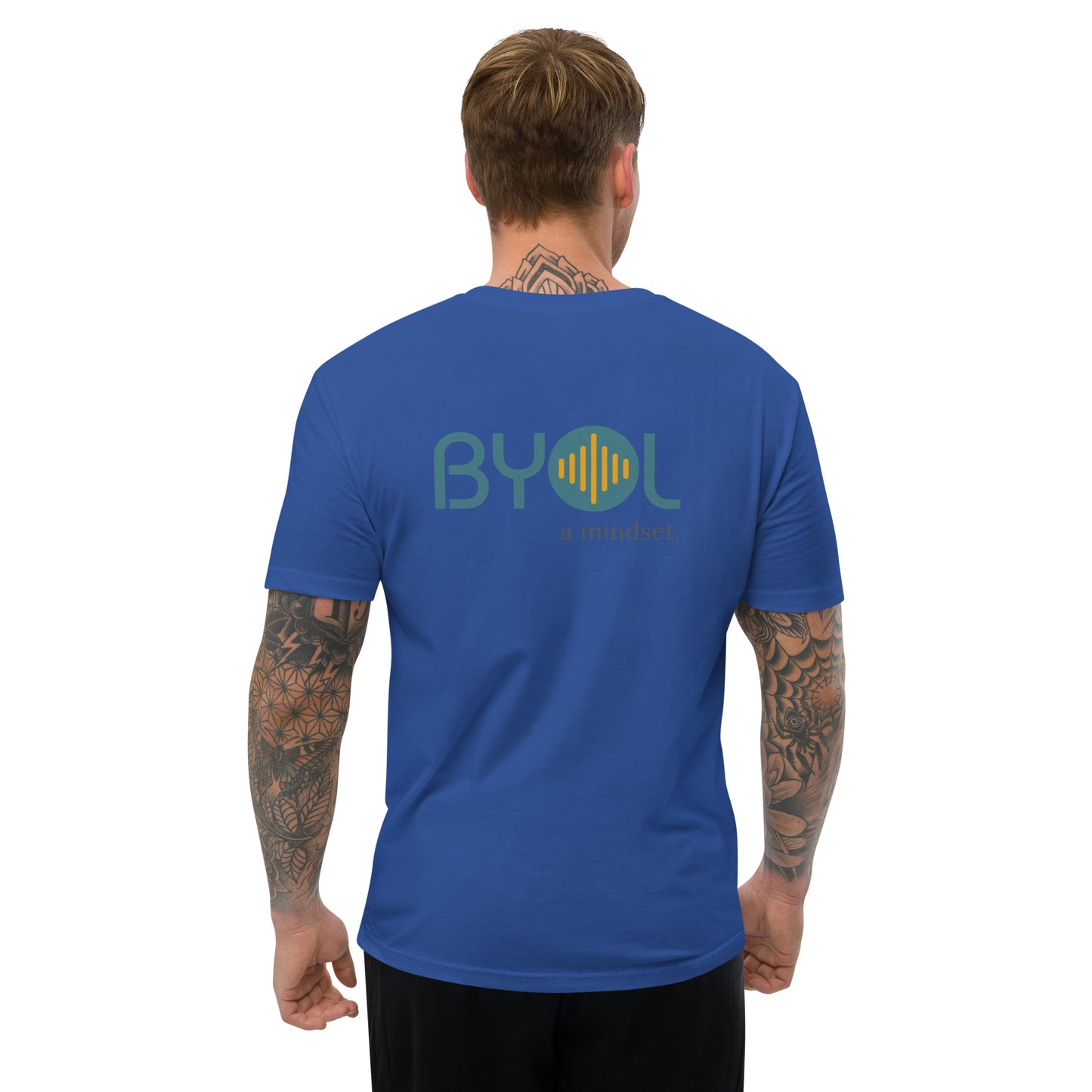 A young man with short blonde hair and arm tattoos wearing a royal blue "BYOL: a mindset" T-shirt, viewed from the back. The T-shirt features the "BYOL" logo in teal and yellow on the back and is available in multiple colors (red, blue, gray, white, plus more) and sizes (S-3XL). The "be you out loud" logo is displayed at the top.