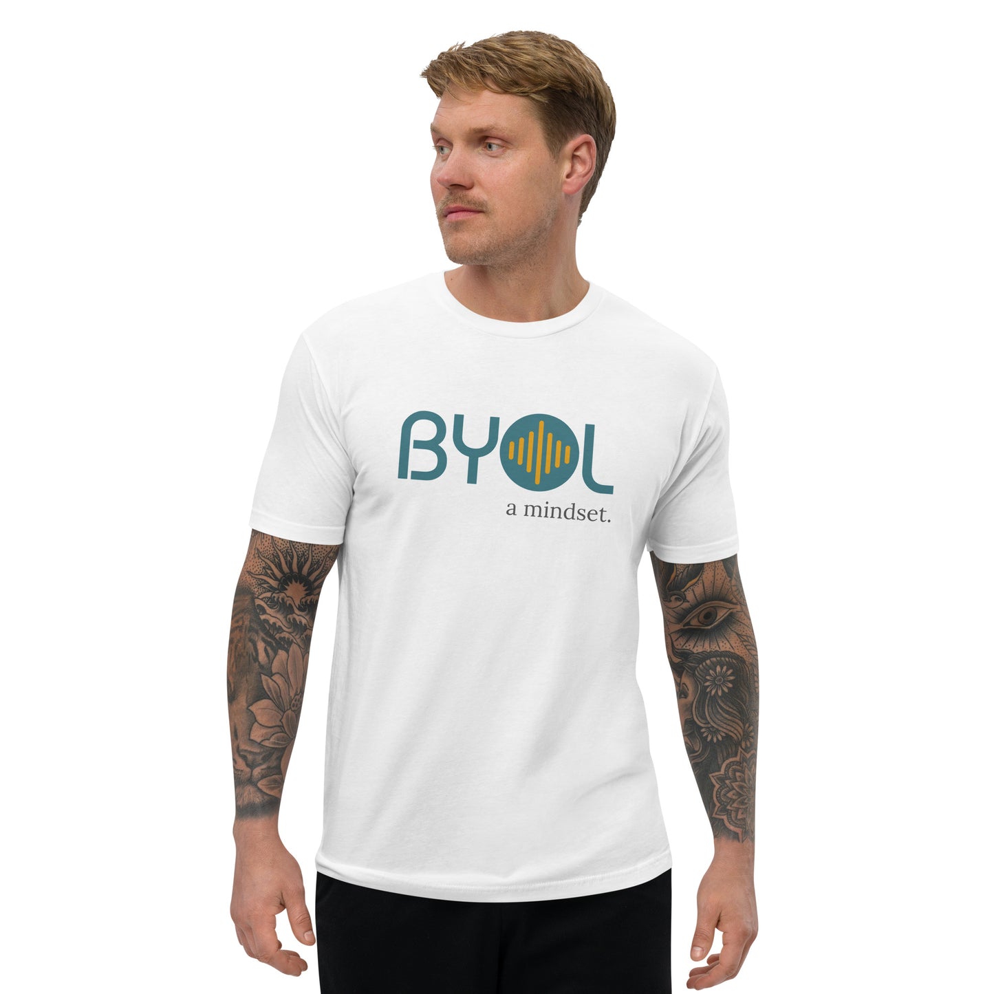 A young man with short blonde hair and arm tattoos wearing a white "BYOL: a mindset" T-shirt, standing and looking to the side. The T-shirt features the "BYOL" logo in teal and yellow on the front and is available in multiple colors (red, blue, gray, white, plus more) and sizes (S-3XL). The "be you out loud" logo is displayed at the top.