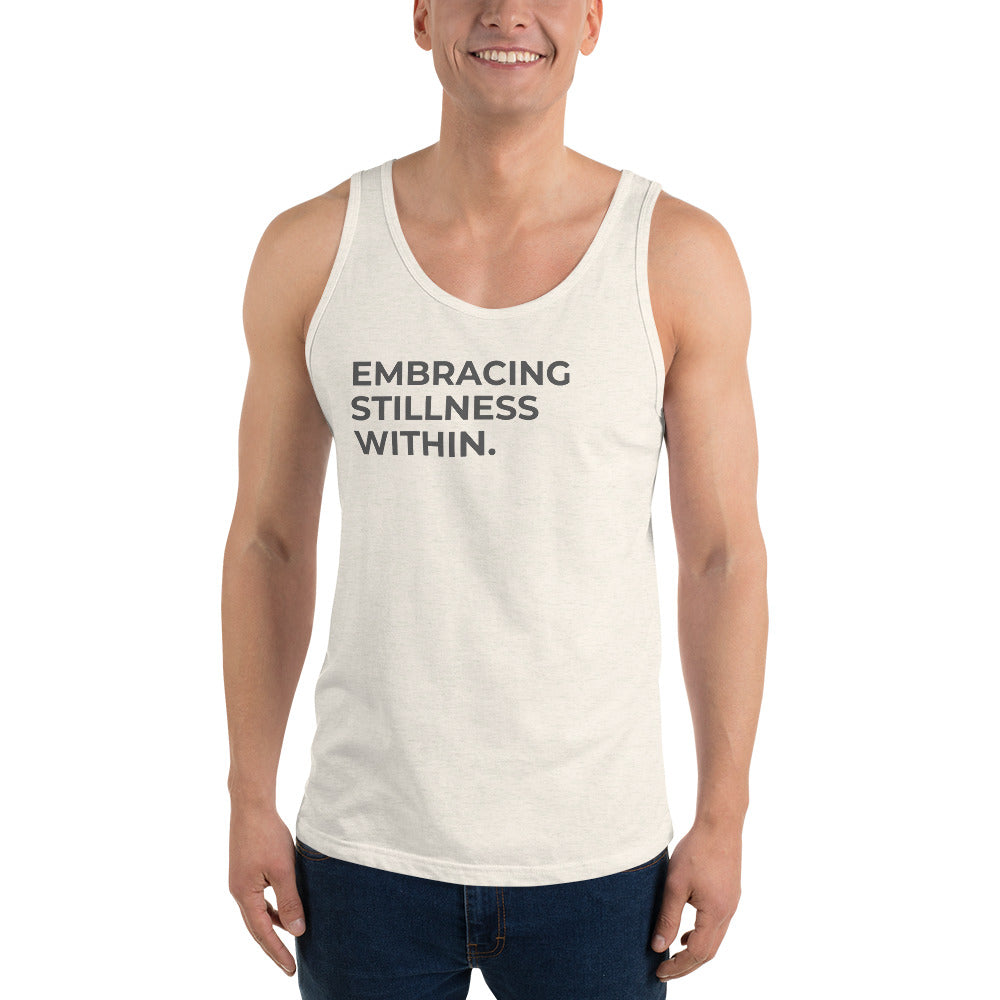 Man wearing a triblend oatmeal sleeveless tank with "Embracing Stillness Within" text. 