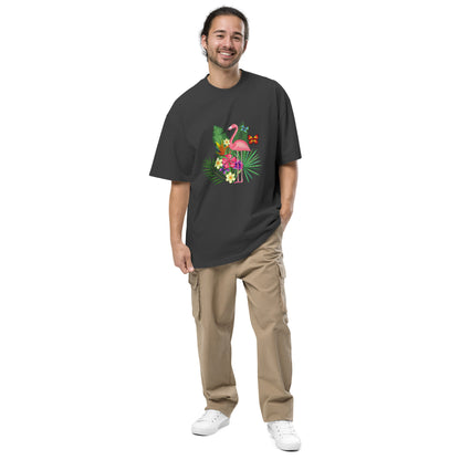 A man with a relaxed smile is wearing a faded black oversized t-shirt with a vibrant graphic of a green frog, tropical flowers, and a butterfly in the center. The casual yet eye-catching shirt is paired with khaki cargo pants and white sneakers, creating an effortlessly cool and nature-inspired outfit.